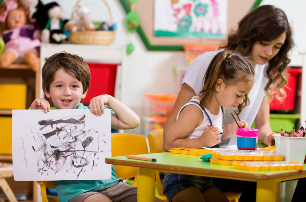 preschoolers painting in classroom with teacher