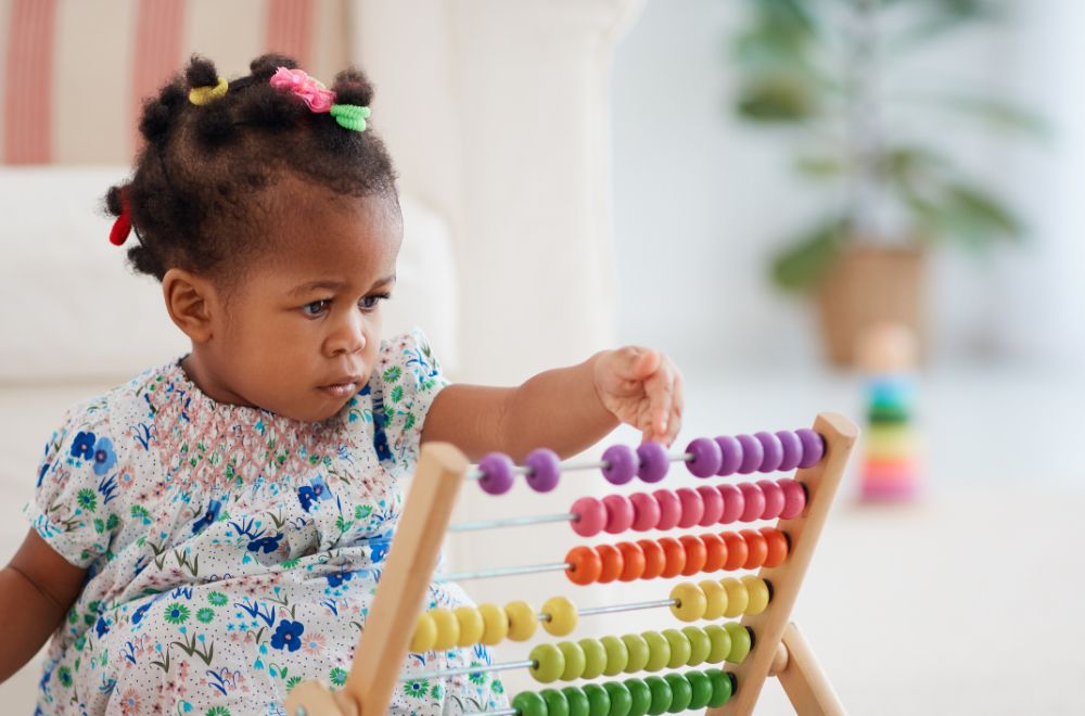 African American baby girl playing colorful abacus toy