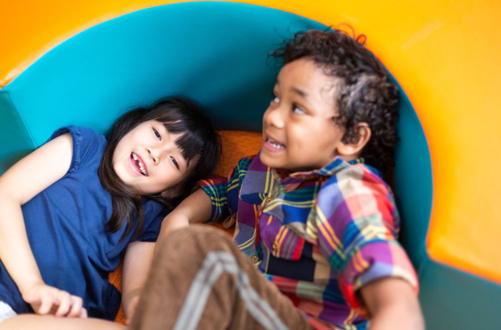 Asian little girl playing with African American boy in playroom