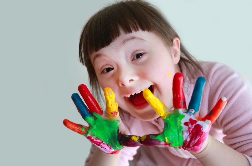 Down's syndrome little girl with painted hands