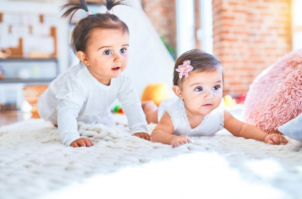 infant happy white girls playing together lying on blanket at daycare